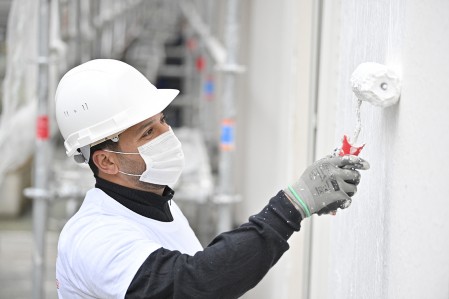 Homme applique un revêtement extérieur sur une façade lors d'un ravalement - Zolpan